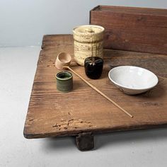 a wooden table topped with two bowls and chopsticks next to a bowl on top of a plate