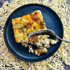 a piece of quiche on a blue plate with a fork and shredded parmesan