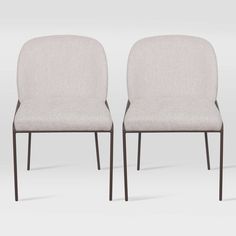 two white chairs sitting next to each other on a gray surface with no one in it