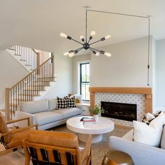 a living room filled with furniture and a fire place in front of a stair case