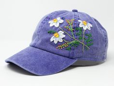 a purple hat with daisies embroidered on it