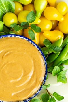 a bowl of peanut butter surrounded by green and yellow peppers