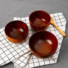 three wooden bowls sitting on top of a cloth