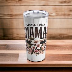 the small town mama tumbler is sitting on top of a wooden table with wood planks behind it