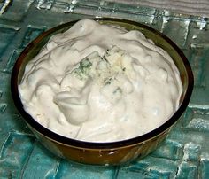 a bowl filled with white sauce sitting on top of a blue cloth covered tablecloth