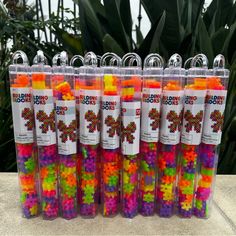 many different colored beads in plastic containers on a table next to some plants and trees