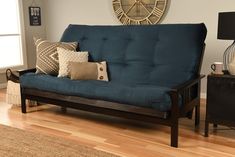 a blue futon sofa with two drawers underneath it and a clock on the wall