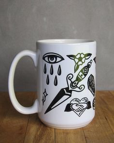 a white coffee mug with black and green designs on the inside is sitting on a wooden table