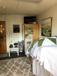 a bed room with a neatly made bed next to a door and a tv on the wall