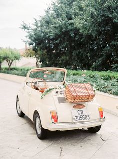 an old white car with luggage on the back