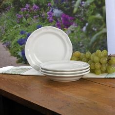 white plates and grapes sit on a wooden table