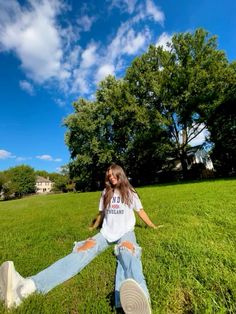 a woman sitting in the grass with her legs spread out and one leg bent up