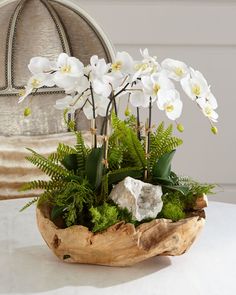 a wooden bowl filled with white flowers on top of a table