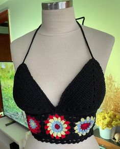 "Unveil the essence of bohemian charm with our handcrafted crochet halter top! This artisanal piece showcases a timeless black base, elegantly contrasted with vibrant granny square accents in red, blue, and cream. Every stitch tells a story of craftsmanship and style. Perfect for sun-soaked festivals or as a unique layering item, this top promises comfort with its soft yarn and brings a splash of color to any outfit. 🌸🌞 It's not just clothing; it's a statement. Embrace your free spirit and sta Black Bohemian Halter Top For The Beach, Bohemian Crochet Halter Neck Top For Festivals, Bohemian Yarn Crochet Top, Fitted Bohemian Crochet Cotton Top, Fitted Bohemian Crochet Top In Cotton Yarn, Fitted Bohemian Crochet Top In Cotton, Bohemian Crochet Halter Neck Crop Top, Bohemian Crochet Crop Top With Halter Neck, Bohemian Crochet Lace Triangle Halter Top