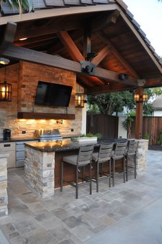 an outdoor kitchen with bar seating and television