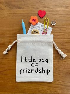 a small bag filled with school supplies on top of a wooden table next to scissors and paper clips