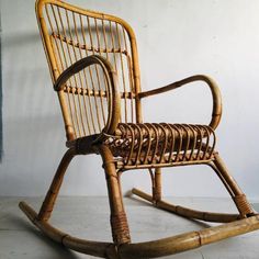 a wicker rocking chair is shown in front of a white wall and grey floor