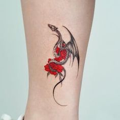 a woman's foot with a dragon tattoo on the ankle and red roses around it