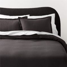 a bed with black and white sheets and pillows