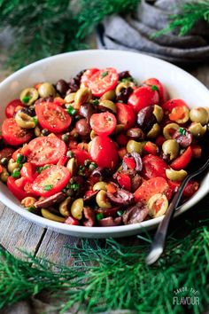 a white bowl filled with tomatoes and olives