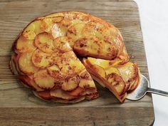 a pineapple upside down cake on a wooden cutting board with a serving spoon next to it