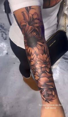 a woman's arm with flowers on it and a black bag in the background