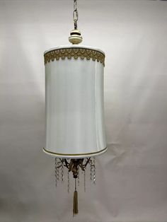 a chandelier hanging from the ceiling with a white lamp shade on it's side