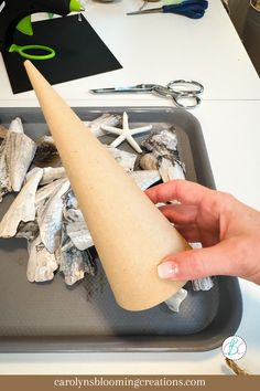 a person holding a paper cone in front of some scissors