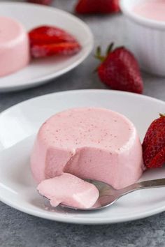 two white plates topped with strawberry cheesecakes and strawberries