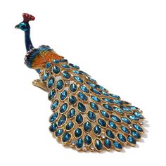 a blue and orange peacock brooch sitting on top of a white surface