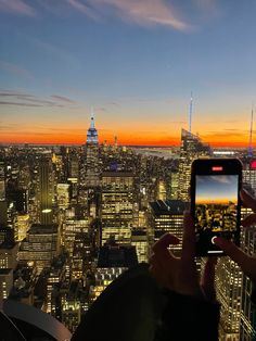 a person taking a photo with their cell phone at the top of a building in new york city