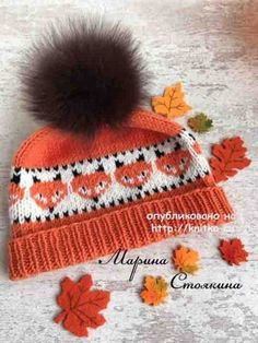 an orange and white knitted hat with a black pom - pom on top