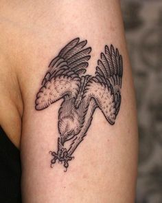 an eagle tattoo on the back of a woman's left arm and shoulder is shown