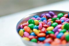 the family m & m logo is shown above a bowl full of colorful candies