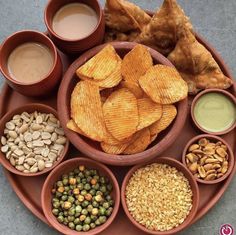 a plate filled with lots of different types of food next to dipping sauces and pita chips