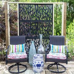 two chairs sitting next to each other in front of a pergolated area with flowers on it