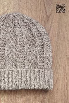 a gray knitted hat sitting on top of a wooden floor