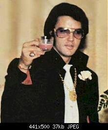 a man in sunglasses and a black jacket is holding a small glass with something on it