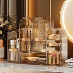 an assortment of cosmetics and perfume bottles on a counter next to a vase with flowers