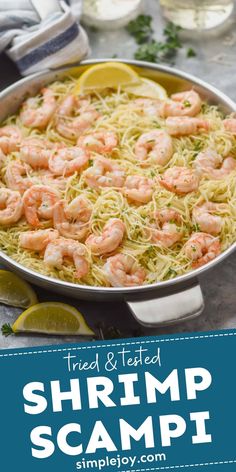 shrimp pasta in a pan with lemon wedges and parmesan cheese on the side