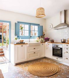 a kitchen with blue and white cabinets, an oven, sink and rug on the floor