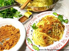 two plates of spaghetti with parsley crumbs on them, next to a pot of pasta sauce