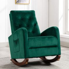 a green rocking chair sitting on top of a floor next to a white wall and window