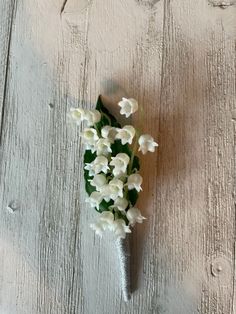 small white flowers are placed on a wooden surface with paint peeling off the wall behind them