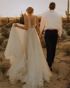 a man and woman are walking through the desert with their back to each other, holding hands