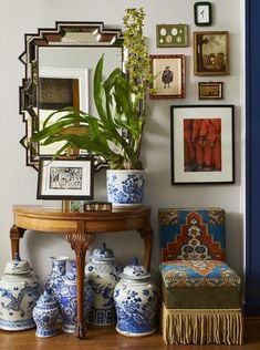 there are many vases and pictures on the wall next to a table with a mirror