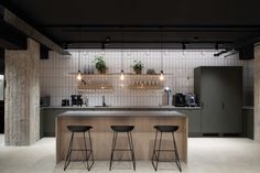 a kitchen with two bar stools in front of it and plants on the wall