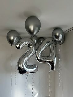 silver balloons shaped like the number twenty five hanging from a ceiling in a room with white walls