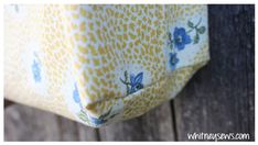 a yellow and blue flowered bag sitting on top of a wooden table