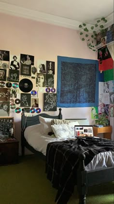 a bed room with a neatly made bed and lots of pictures on the wall above it